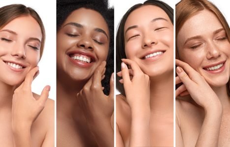 Happy diverse women enjoying skin softness Optimistic multiethnic women with closed eyes smiling and touching perfect clean skin while representing skincare industry